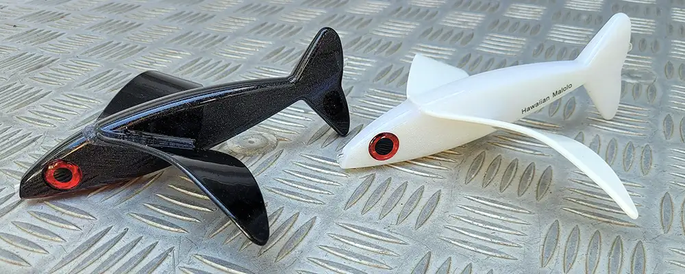 Black and white fishing lures sitting next to one another on metal background